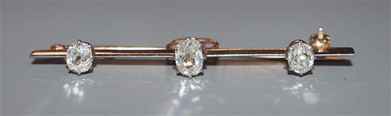 An early 20th century yellow metal and three stone oval cushion cut diamond set bar brooch, 52mm.